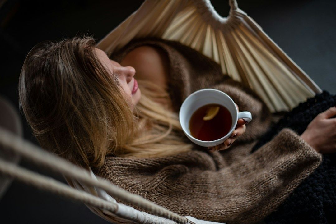 Woman relaxing in a hammock while holding a cup of tea