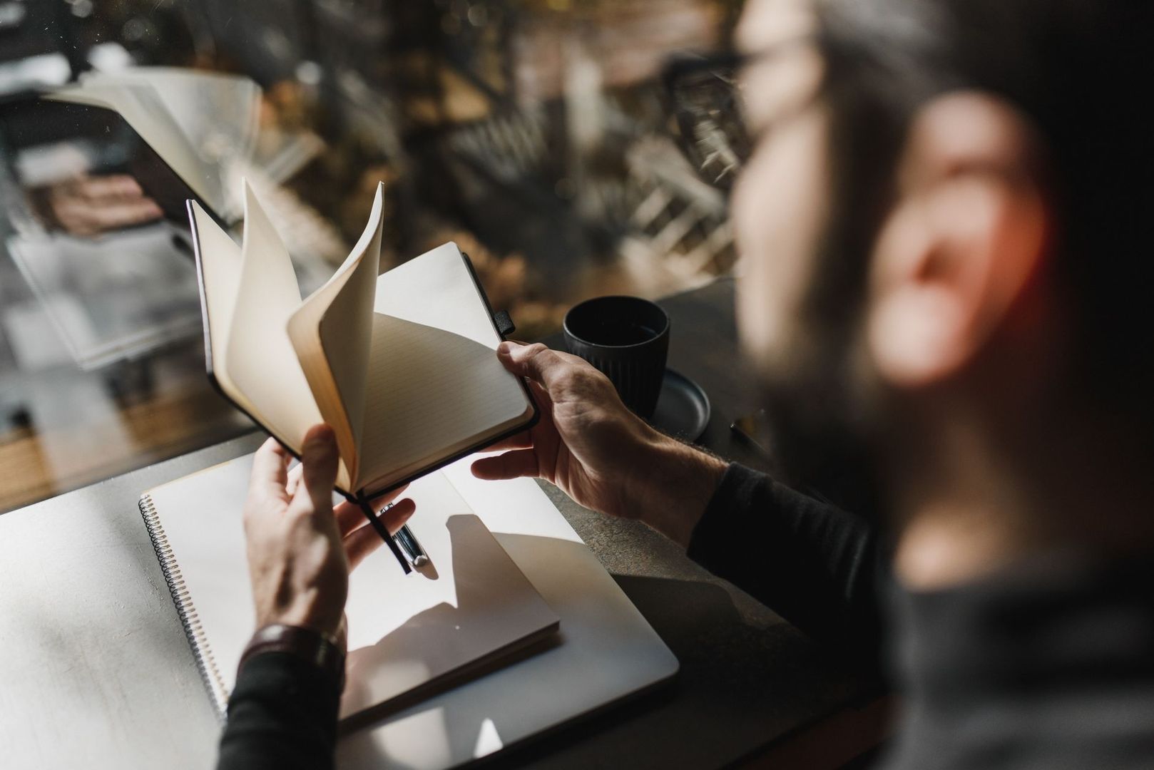 Person quietly reading an open notebook beside a cup of coffee